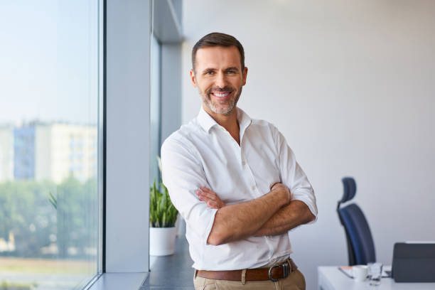 Portrait of smiling mid adult businessman standing at corporate office