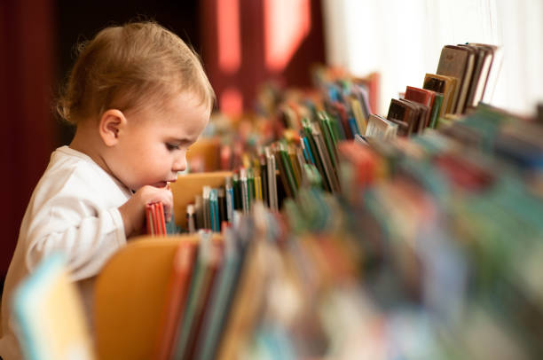 Little girl flicking trough books in a library. Natural light.