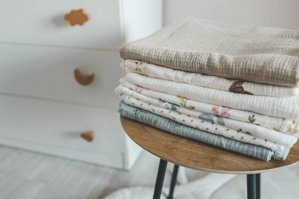 Stack of baby muslin blankets and newborn diapers.