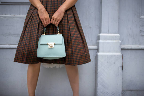 Unrecognizable fashionable young woman holding a purse while standing on the street in Vienna.